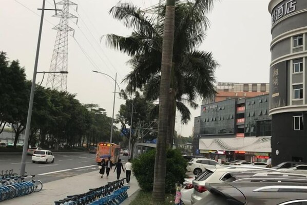 Une rue bordée de voitures garées, avec un autobus et des piétons.