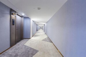 A long, narrow hotel corridor with doors on one side and a carpeted floor. - Movie Hotel (Guangzhou Pazhou Exhibition Center Store) (Guangzhou)