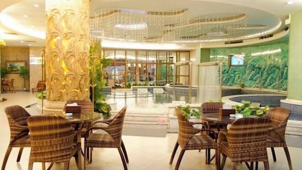 A lobby with a pool, wicker chairs, and a large decorative column. - Movie Hotel (Guangzhou Pazhou Exhibition Center Store) (Guangzhou)
