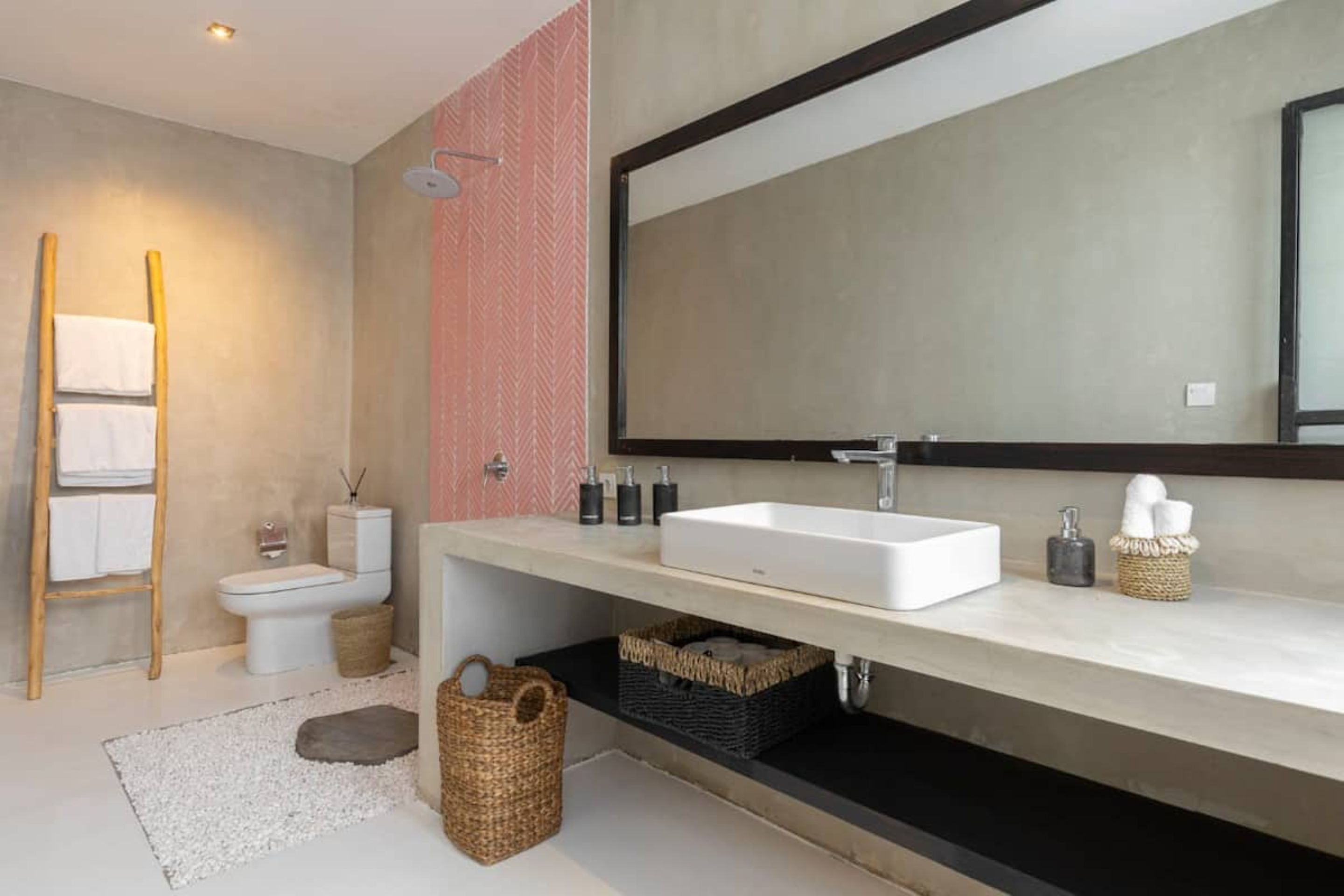 A modern bathroom with a large mirror, white sink, and a towel rack.