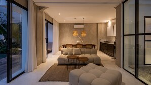 Un salon moderne avec un canapé, deux tables rondes et une grande fenêtre.