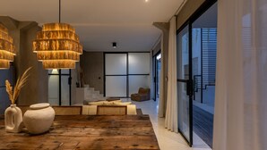 Un intérieur moderne avec une table à manger en bois, deux vases en céramique et une grande fenêtre donnant sur un immeuble.