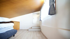 A bedroom with a lofted sleeping area, a wooden ceiling, a window with a curtain, and a staircase leading to an upper level. - ITOMAN SEA Pension Odo  MIM (Itoman)