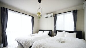 A hotel room with two beds, a modern air conditioning unit, and a hanging light fixture. - ITOMAN SEA Pension Odo  MIM (Itoman)