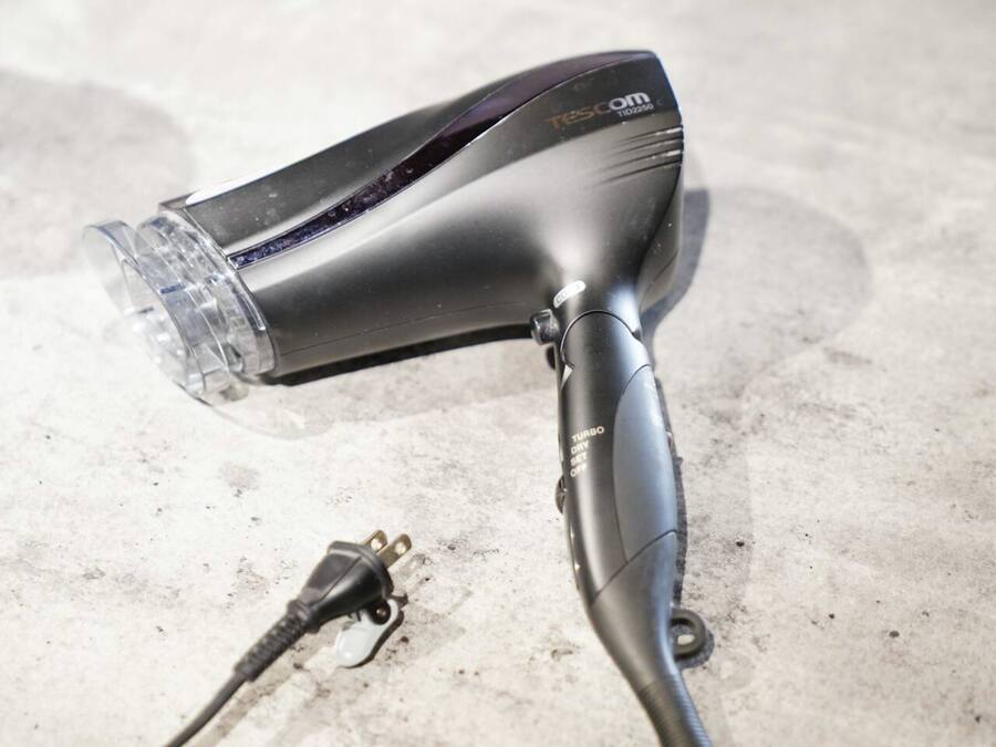 A hair dryer with a transparent nozzle and a power cord.