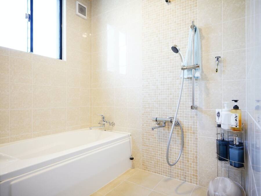 Een moderne badkamer met een badkuip, douche en betegelde wanden.