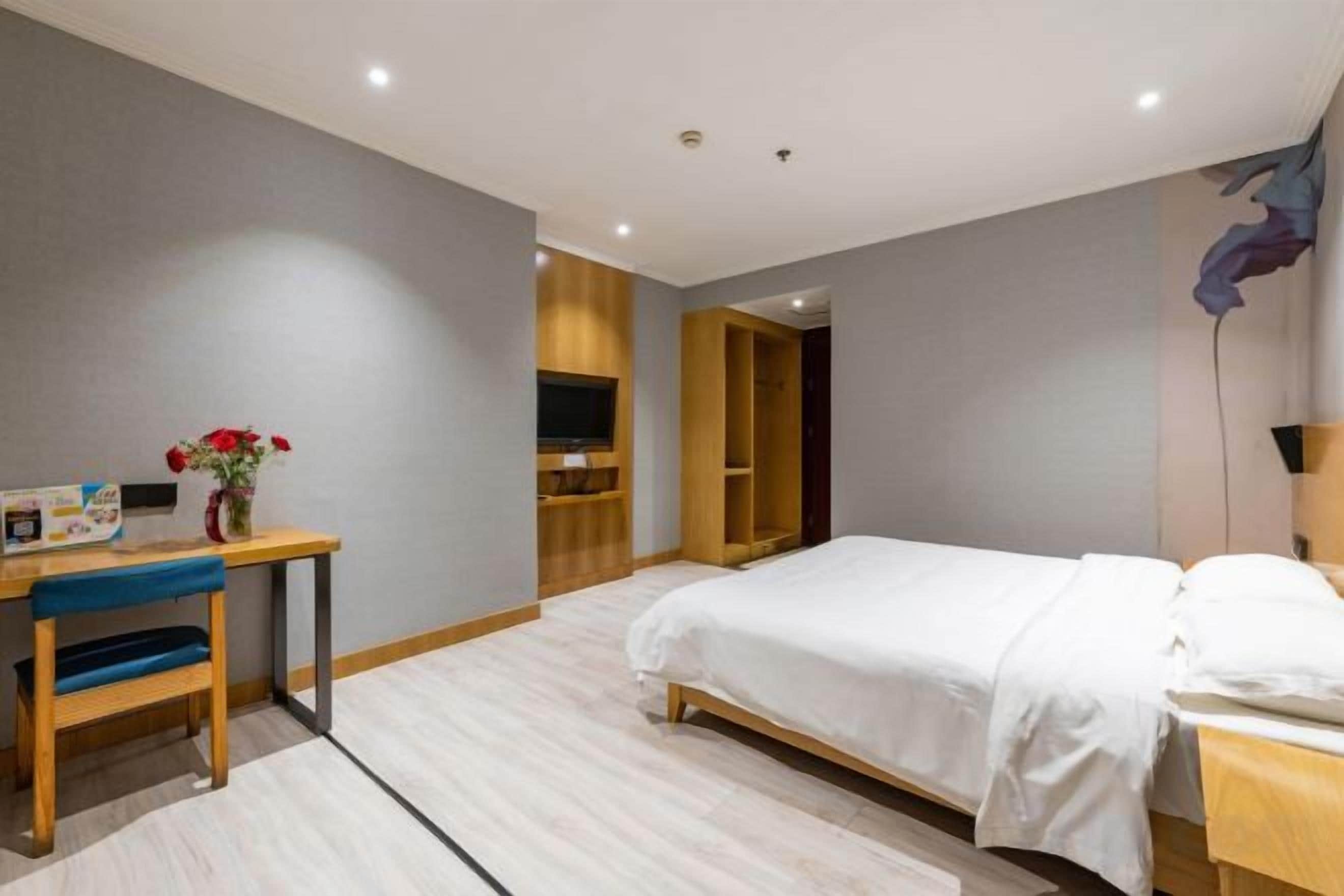 Ein Hotelzimmer mit einem Bett, einem Schreibtisch mit Stuhl, einem Fernseher und einem Kleiderschrank.
