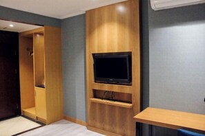 Una habitación con televisión integrada, paneles de madera, un estante pequeño y un escritorio.