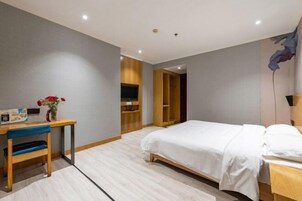 Quarto de hotel moderno com cama, escrivaninha, cadeira, televisão e guarda-roupa.