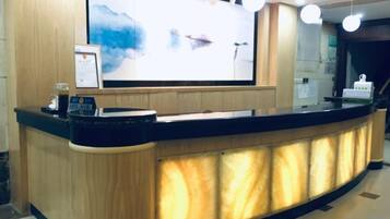 A reception desk with a digital screen, a coffee machine, and a framed picture.