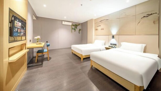 Habitación de hotel con dos camas, un escritorio, una silla y un televisor.