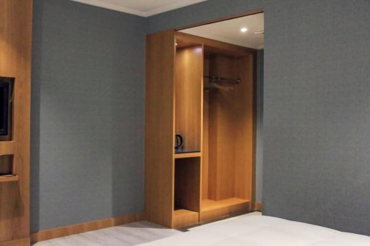Un dormitorio con cama, armario de madera y estante empotrado para la televisión.