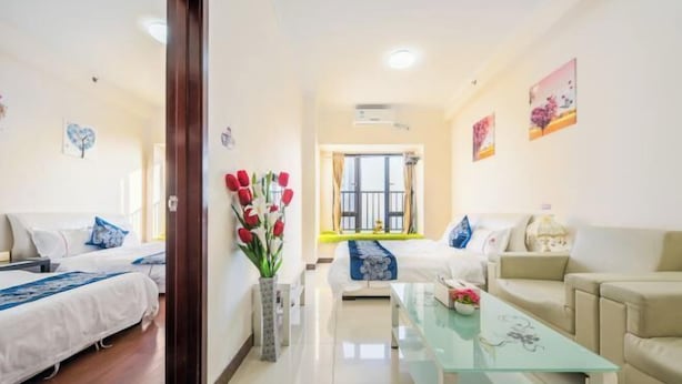 Habitació d'hotel amb dos llits, un sofà, una taula de cafè de vidre i un ram de flors.