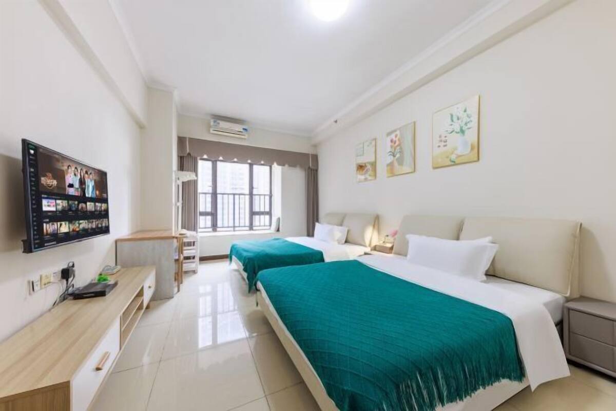 Habitación de hotel con dos camas, televisión, escritorio y obras de arte en las paredes.