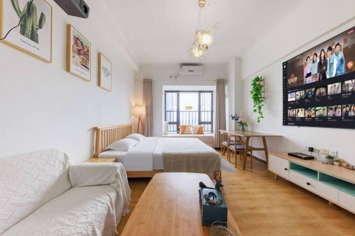 Una habitación de hotel moderna con cama, sofá, escritorio y televisor montado en la pared.