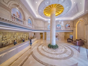 A grand lobby with a central column, a reception desk, and a mural. - Vienna International Hotel (Wuhan)