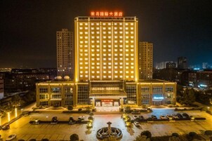 Un hotel de varios pisos con entrada central y un estacionamiento al frente.