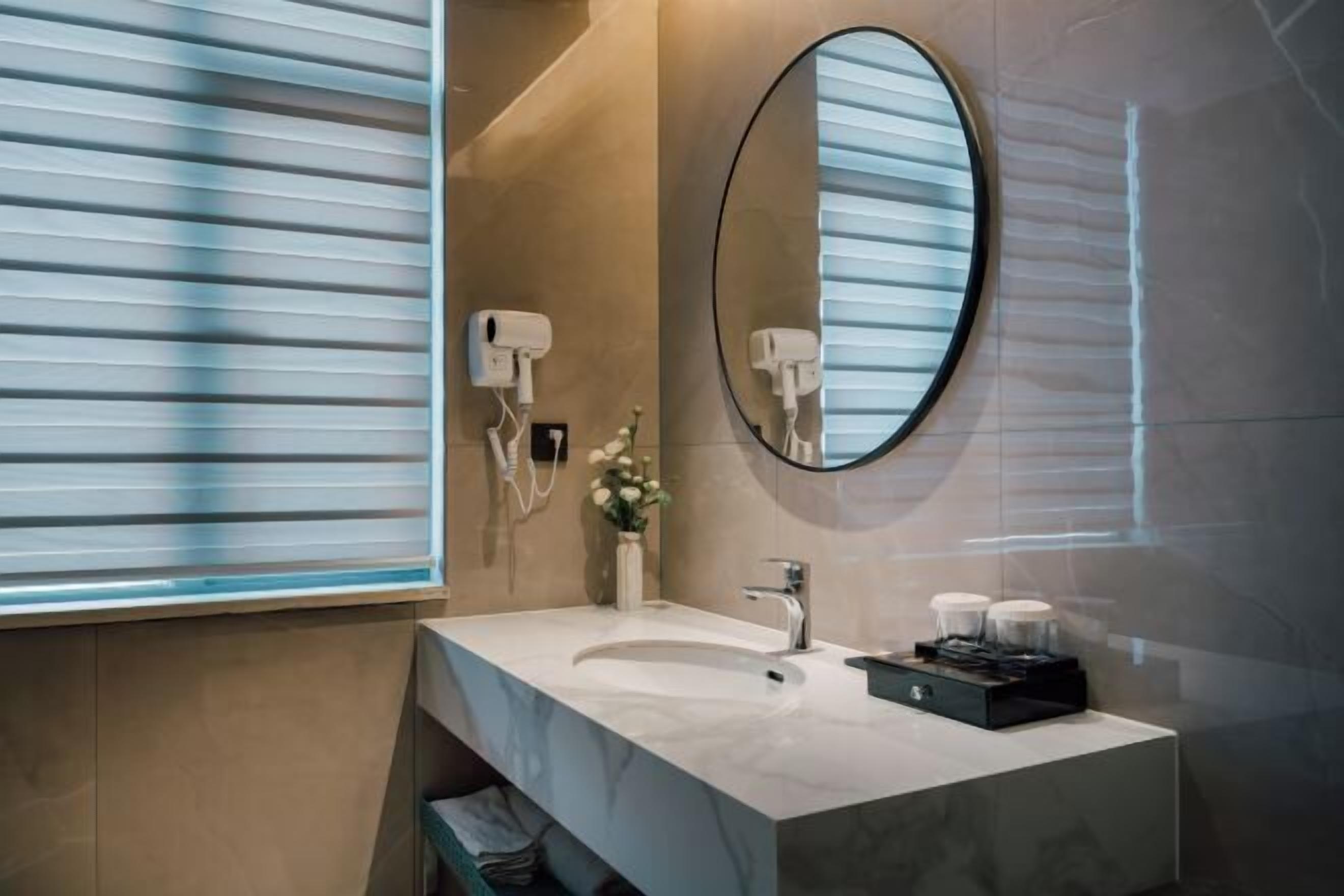 A modern bathroom with a large mirror, a sink, and two hair dryers mounted on the wall.