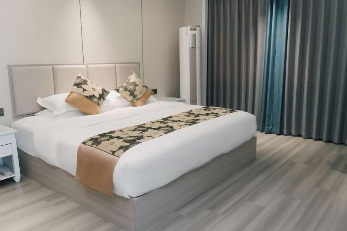 Une chambre d’hôtel moderne avec un grand lit, une table de chevet et un climatiseur fixé au mur.