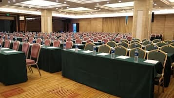 Un salón de conferencias con filas de mesas y sillas, equipado con botellas de agua y tarjetas de identificación.