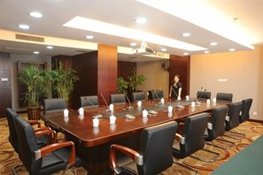 A conference room with a long table, multiple chairs, and a person standing by the table. - Jianning Hotel (Jianning)