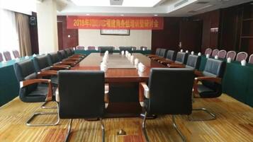 A conference room with a long table, chairs, and a banner on the wall.