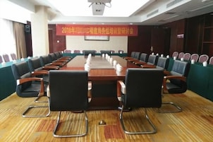 A conference room with a long table, chairs, and a banner on the wall.
