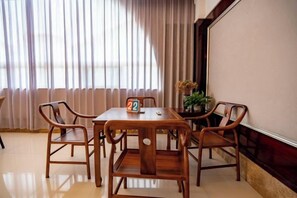 A dining area with a wooden table and chairs, a number card, and a potted plant. - Jianning Hotel (Jianning)