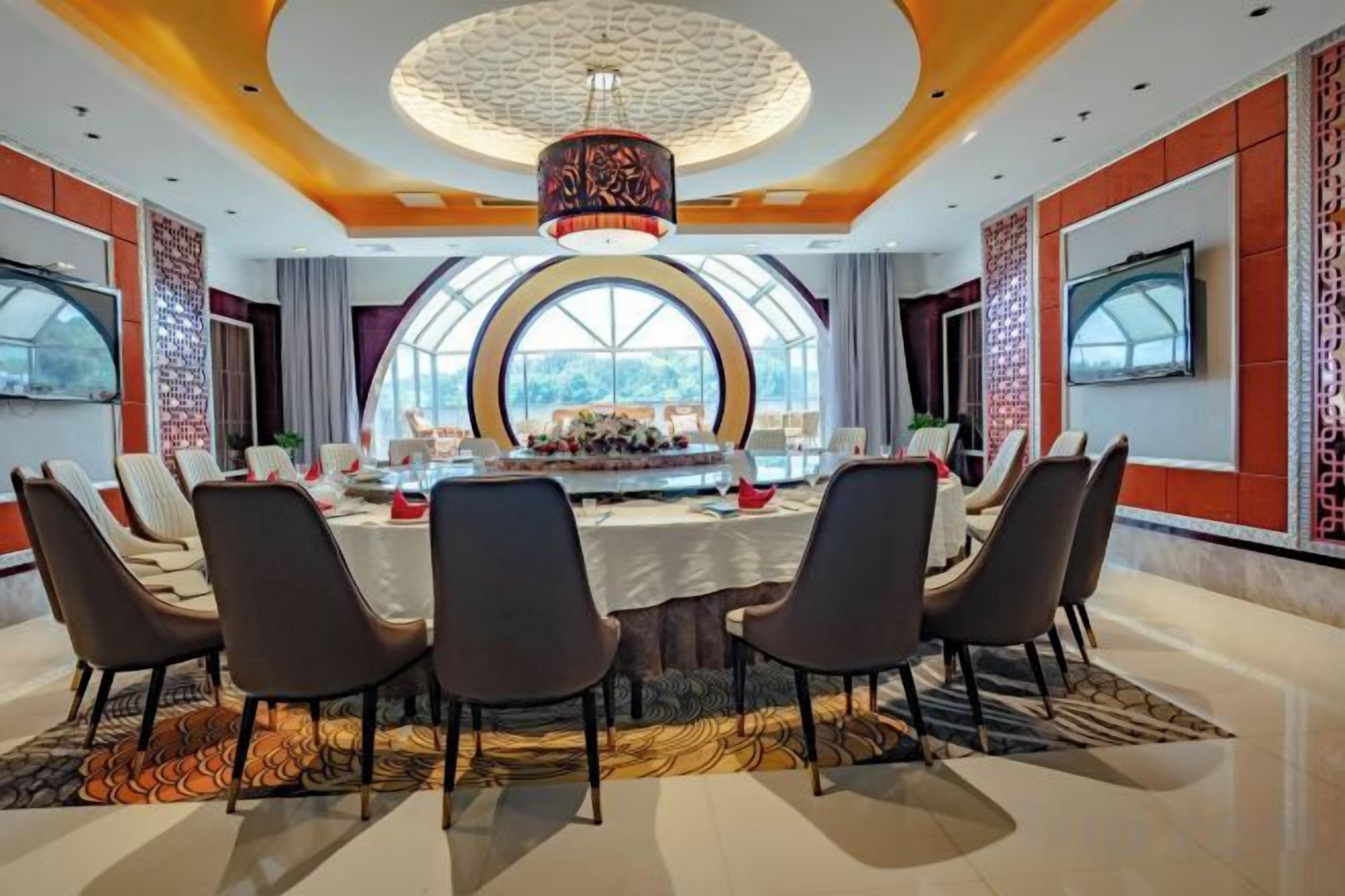 A conference room with a round table, chairs, and a large screen.