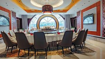 A conference room with a round table, chairs, and a large screen.