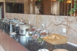 A buffet setup with various food containers and a basket of bread. - Jianning Hotel (Jianning)