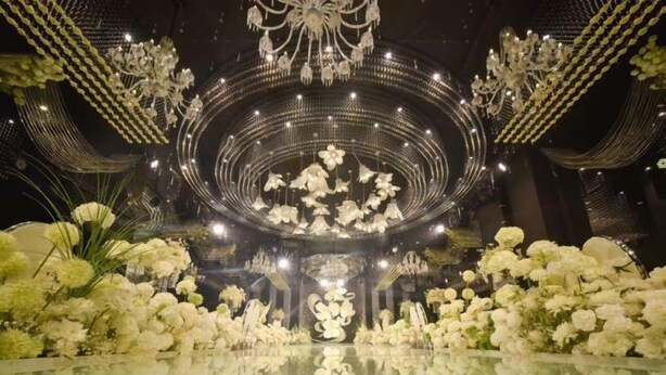 A circular floral arrangement with a chandelier above, surrounded by white flowers and greenery.