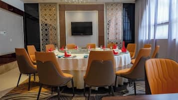 A conference room with a round table, orange chairs, a flat-screen TV, and a decorative screen on the wall.