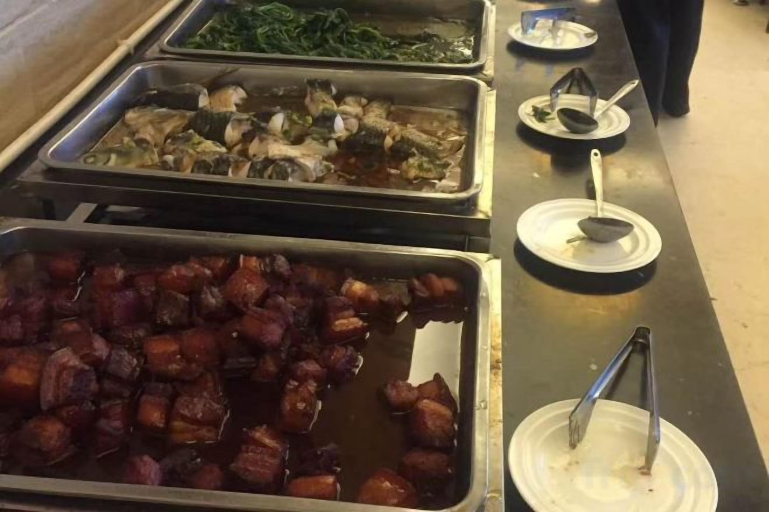 A buffet line with various dishes, including meats and vegetables.