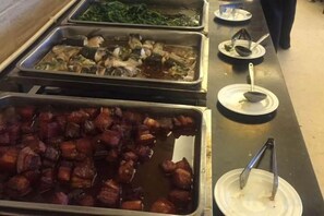 Una barra de buffet con diversos platos, incluyendo carnes y verduras.