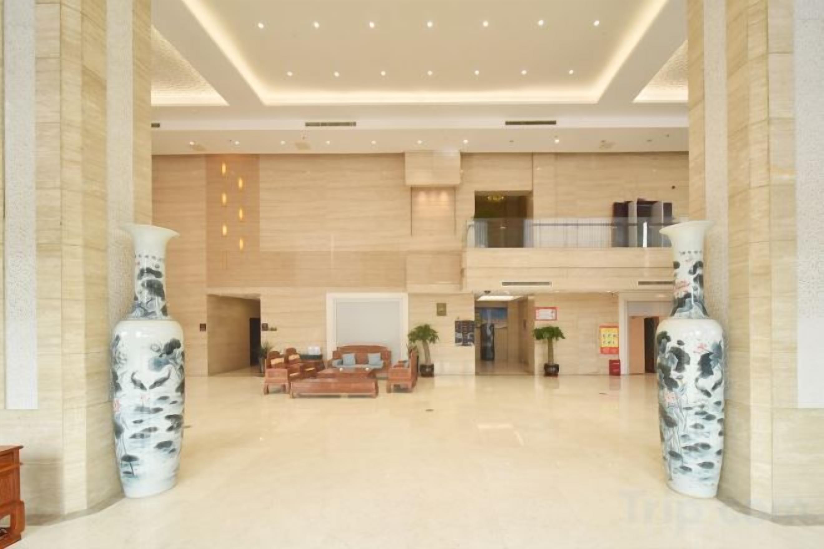 A spacious lobby with a high ceiling, large vases, and a reception desk.