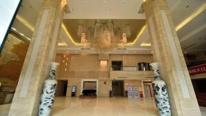 A spacious lobby with marble flooring, a chandelier, and two large vases.