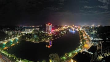 A nighttime cityscape with a river, illuminated buildings, and a bridge.