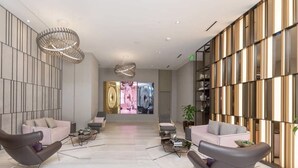 Un vestíbulo moderno con una gran pantalla de televisión, mobiliario contemporáneo y una lámpara decorativa.