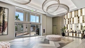 Un vestíbulo amplio con una zona de estar generosa, una lámpara moderna y vistas a través de puertas de cristal.
