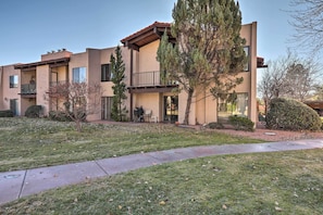 A two-story building with a balcony, a patio, and a well-maintained lawn.
