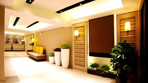 A modern hotel lobby with a reception desk, seating area, and decorative lighting. - Home Inn Plus (Changping)