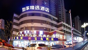 A hotel with a prominent sign, multiple floors, and a parking area with cars. - Home Inn Plus (Changping)