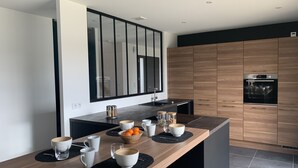 Une cuisine moderne dotée d’un îlot central en bois, de plans de travail noirs et d’un four encastré.