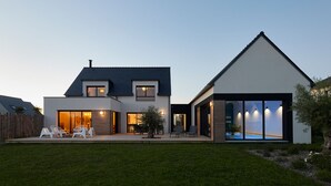 Une maison moderne à deux étages, dotée d’un grand jardin, d’une piscine et d’une pelouse bien entretenue.