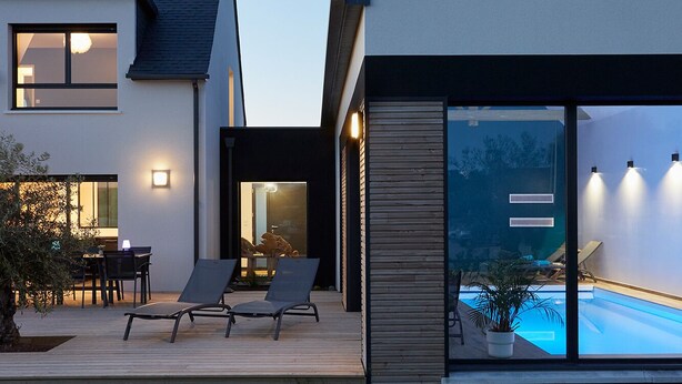 Une maison moderne dotée d’une piscine, d’un espace salon extérieur et d’une terrasse bien éclairée.
