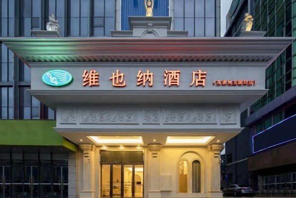 A hotel entrance with a sign in Chinese characters, a statue above the entrance, and a modern building facade. - Vienna Hotel (Lingshan Liufengshan Pedestrian Street) (Lingshan)