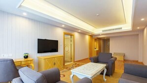 A modern living room with a flat-screen TV, grey sofas, a white coffee table, and a yellow cabinet. - Vienna Hotel (Lingshan Liufengshan Pedestrian Street) (Lingshan)