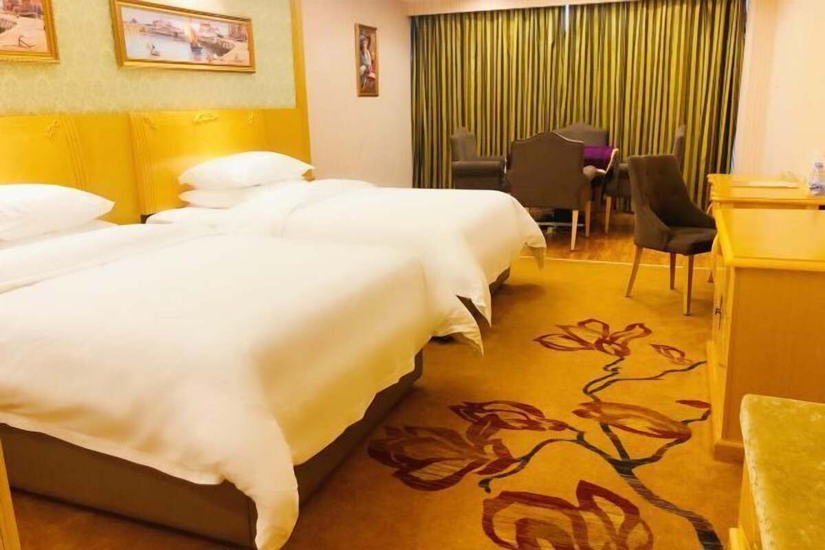 A hotel room with a bed, a desk, a chair, and a curtain.