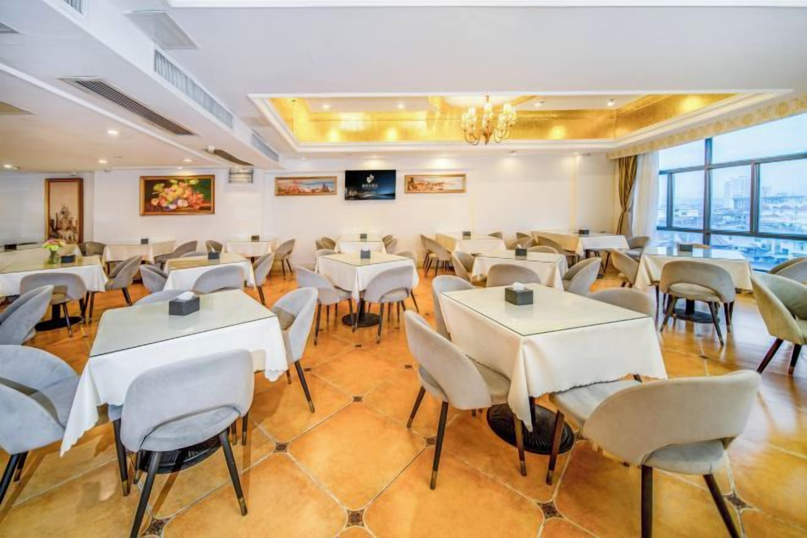 Un espace repas comprenant plusieurs tables et chaises, un lustre et des œuvres d’art accrochées aux murs.